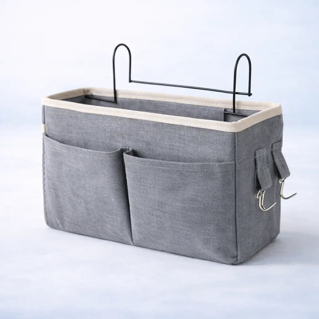 Bedside Baby Organiser – Gray storage caddy with multiple pockets and a beige top on a light blue background