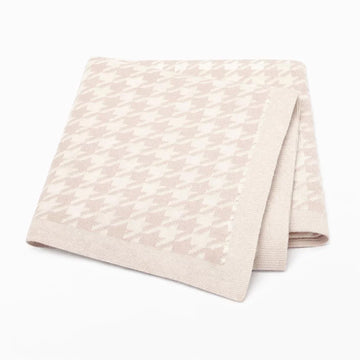 Folded beige blanket with houndstooth pattern on white background