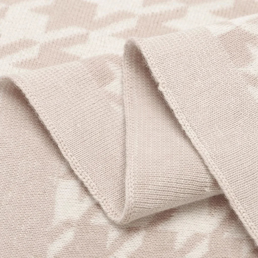 Close-up of soft beige knit blanket with textured geometric pattern.