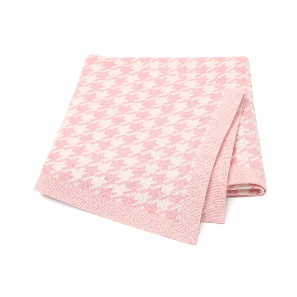 Pink houndstooth patterned blanket neatly folded on a white background.