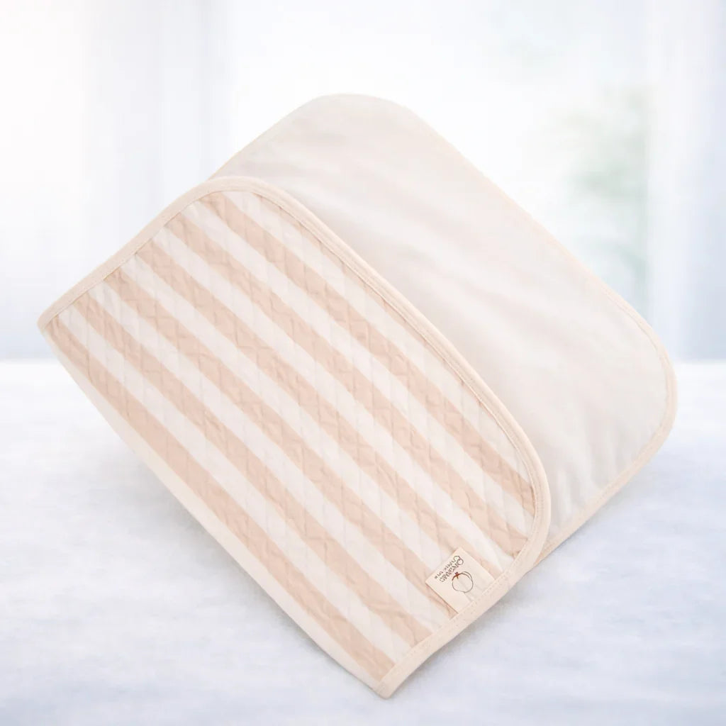 Washable beige striped cot pad on soft white surface, nursery bedding accessory