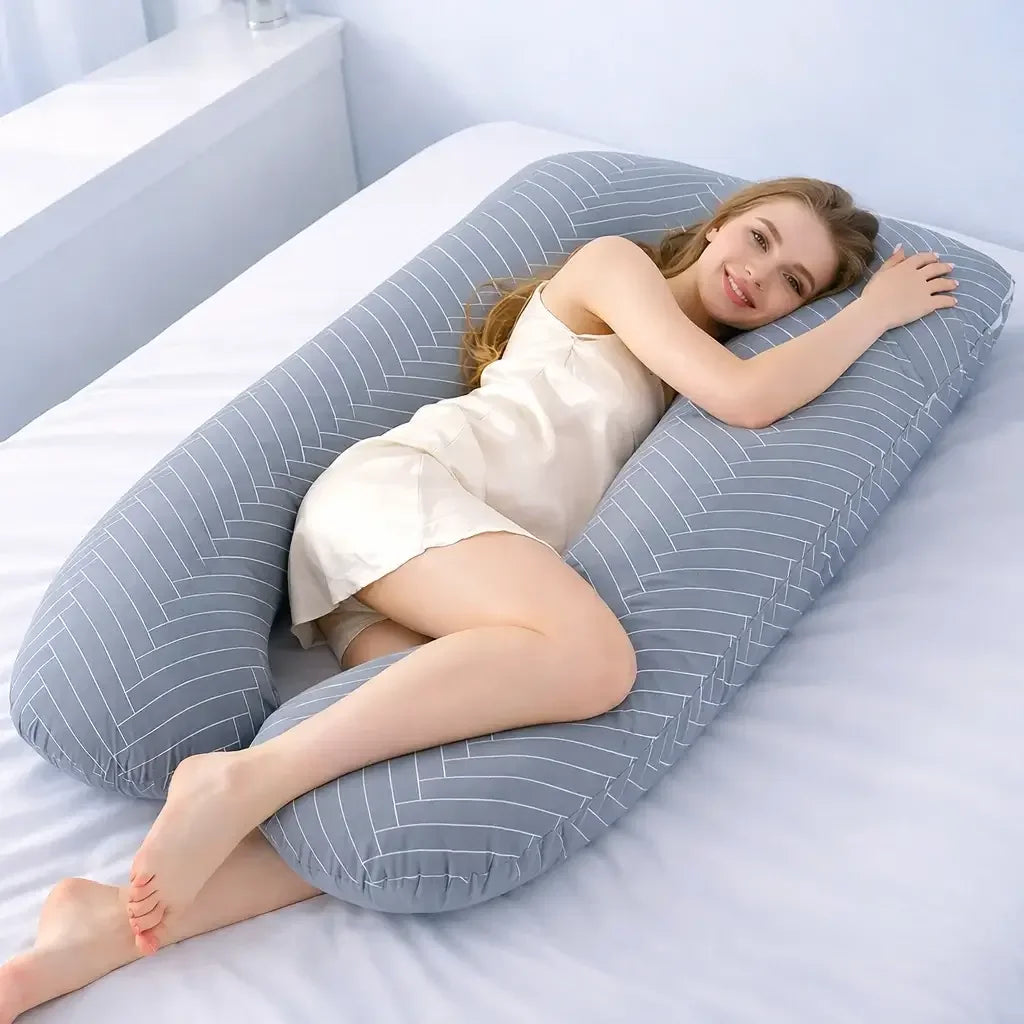 Woman relaxing on bed with large U-shaped cotton stripe pregnancy pillow