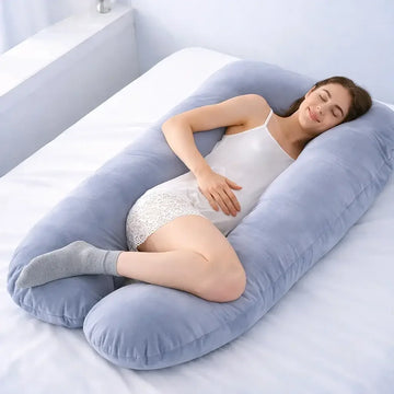 Woman sleeping on bed with large U-shaped fleece pregnancy pillow
