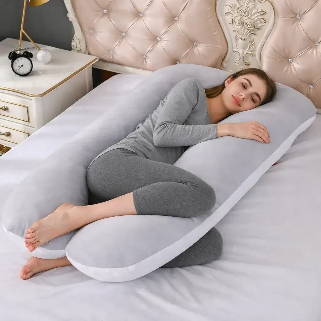 Woman sleeping on large grey and white fleece pregnancy pillow on bed