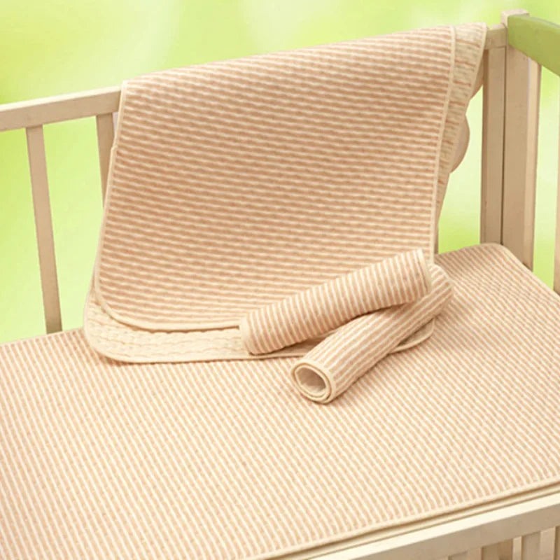 Beige striped baby blanket set on a crib, soft nursery bedding