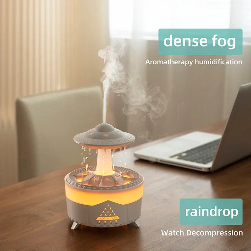 UFO-shaped aromatherapy humidifier with LED lights emitting mist on a desk near a laptop