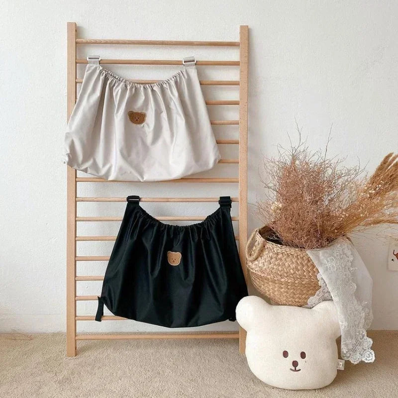 Reusable Stroller Pouch - Two bear-face cloth storage bags hanging on a wooden rack, with a bear-shaped pillow and dried flowers in a woven basket nearby.