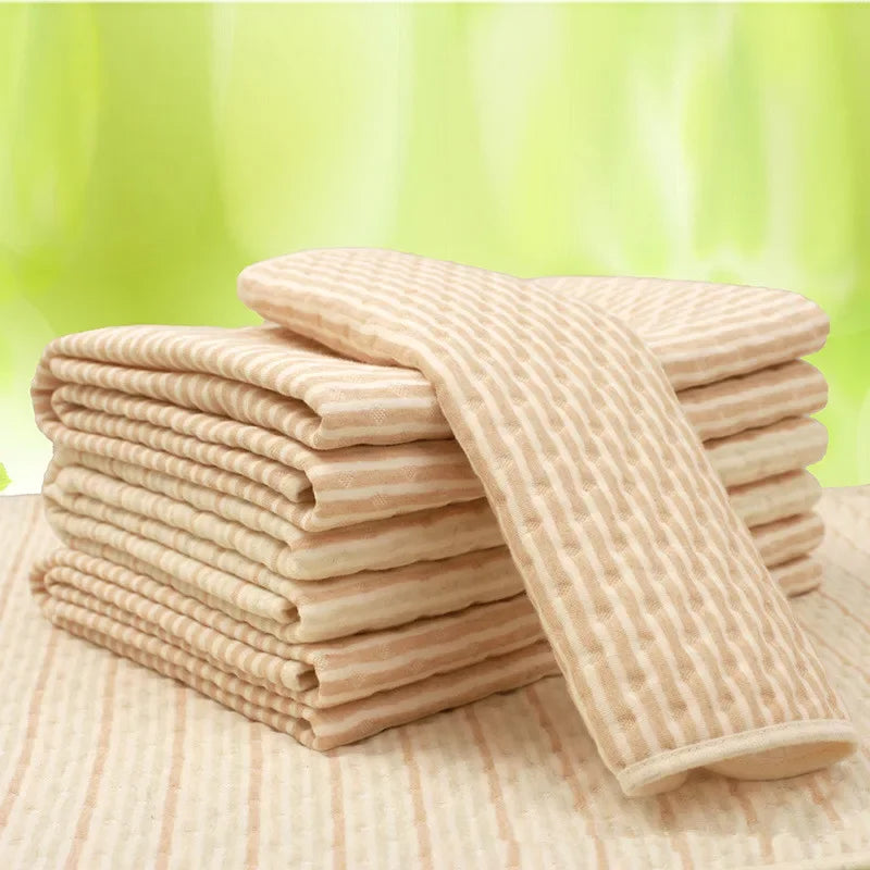 Stack of soft beige striped towels neatly folded on a textured surface