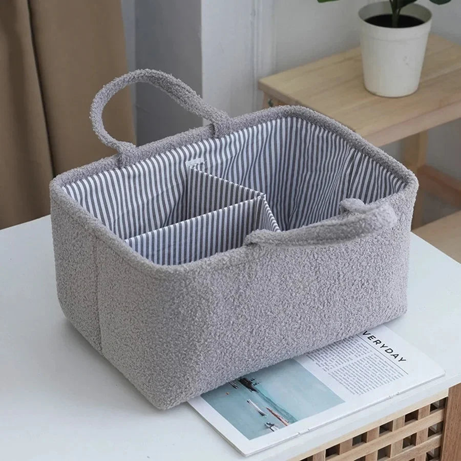 Grey fabric storage basket with handles and striped interior on a table