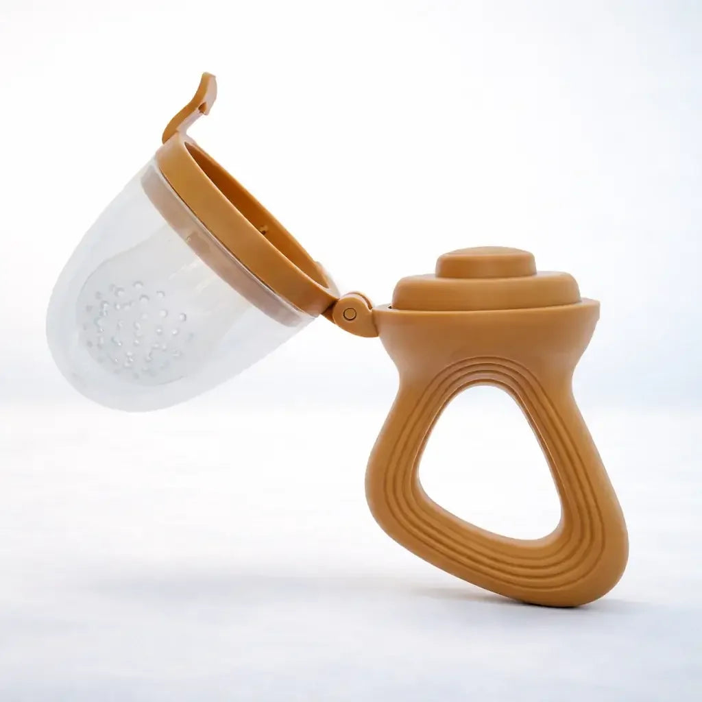 Brown silicone baby fruit feeder with open lid and ergonomic handle on white background
