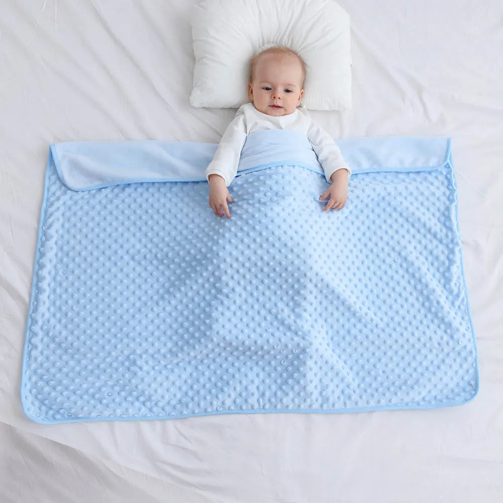 Baby wrapped in autumn winter baby blanket on bed, offering warmth and comfort for cooler days.