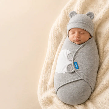 Newborn adjustable swaddle in gray, snugly wrapped with bear ears hat, promoting calm and secure sleep for babies.