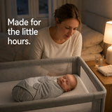 Mom watching her sleeping baby wrapped in an adjustable cotton swaddle during nighttime.