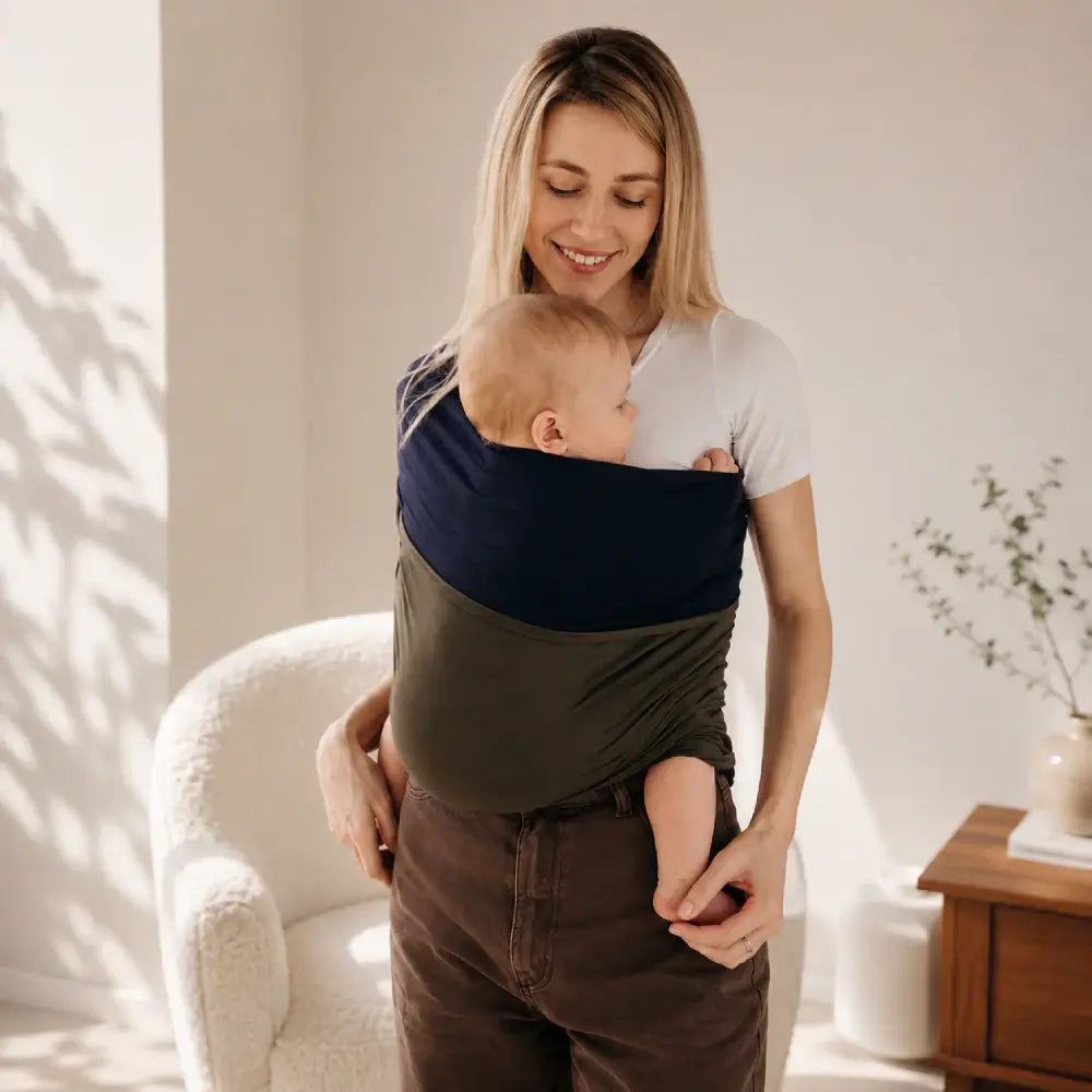 Woman using the baby wrap carrier to bond with her baby in a cozy indoor setting.